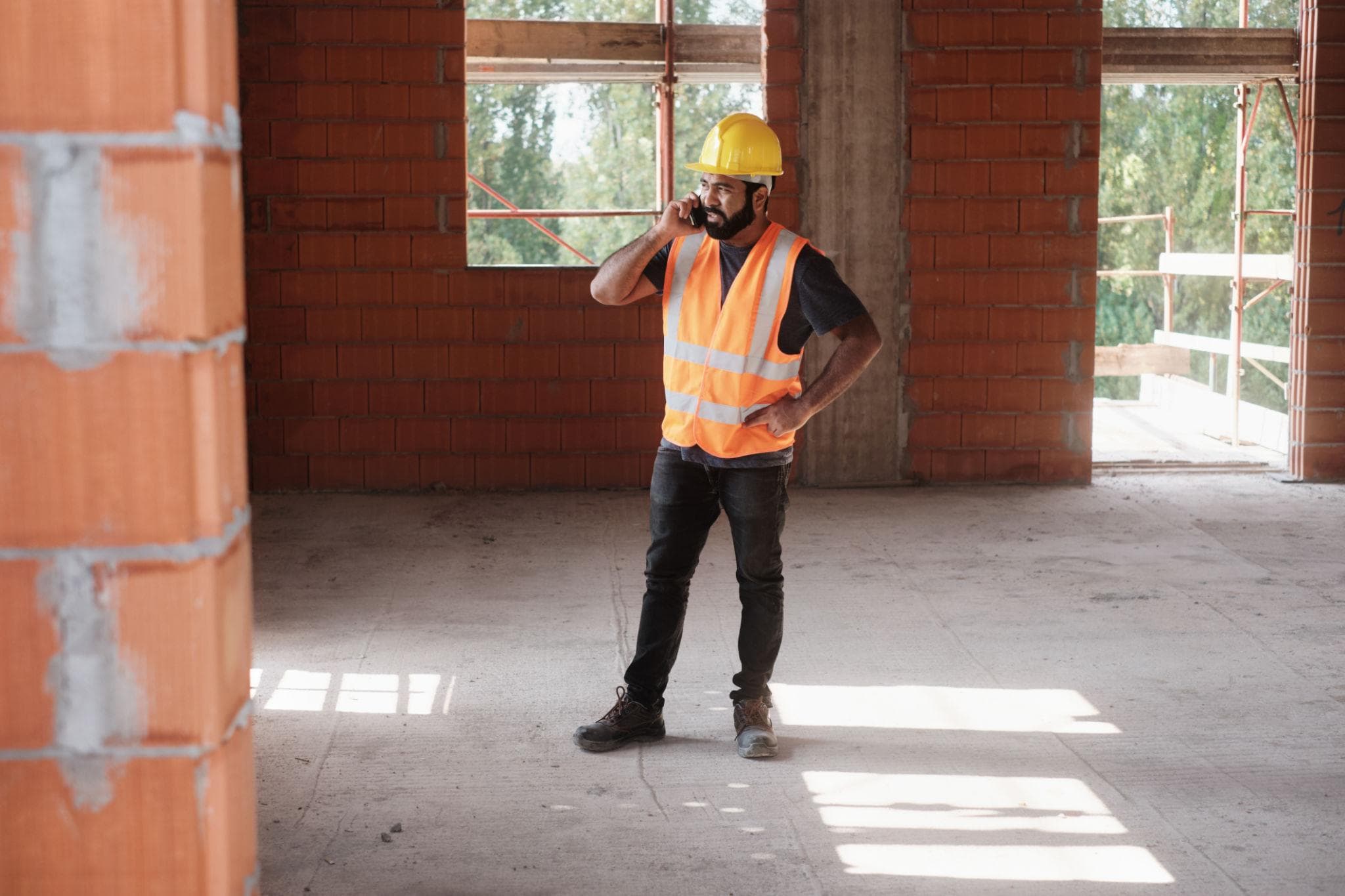 Maestro en obra habla por teléfono en una construcción.